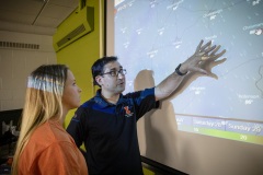 A crop sciences instructor  discusses a projected weather map with an undergraduate female student.